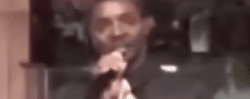 Blurry person holding microphone, speaking indoors.